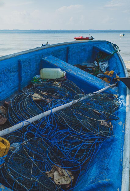 Barco de pesca azul con redes en una playa