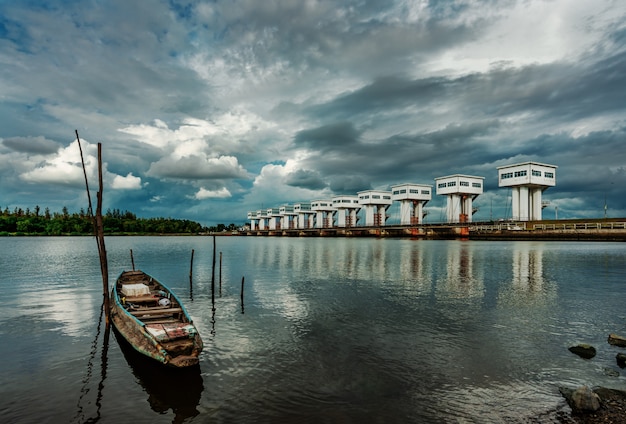 Barco de pesca y barrera de agua y río con cielo tormentoso