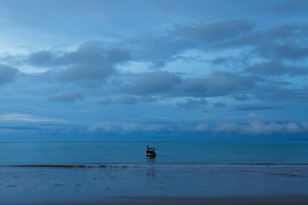 Barco de pesca flotando en un mar tranquilo cerca de la playa de arena