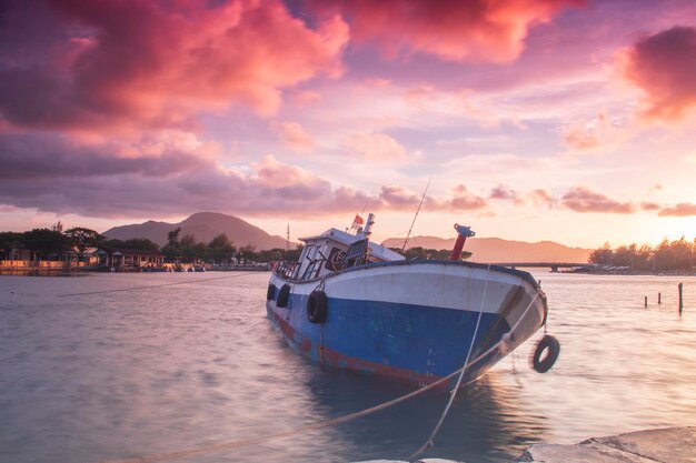 Barco de pesca con fondo de puesta de sol