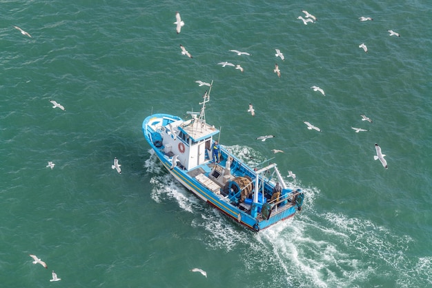 Foto barco de pesca y gaviotas en el mar.