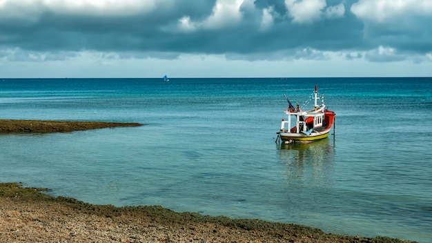 Barco de pesca en el horizonte del océano con cielo nublado.