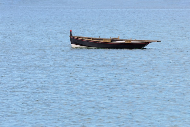 Foto barco de pesca de madera con motor anclado en el mar, paisaje natural tranquilo