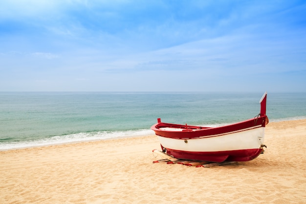 Barco de pesca de madera en una playa de arena