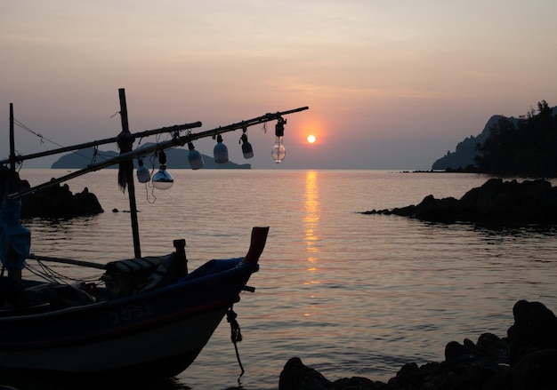 Un barco de pesca parado en la costa al atardecer