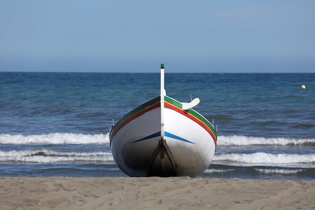 Foto barco de pesca en la playa con cielo azul