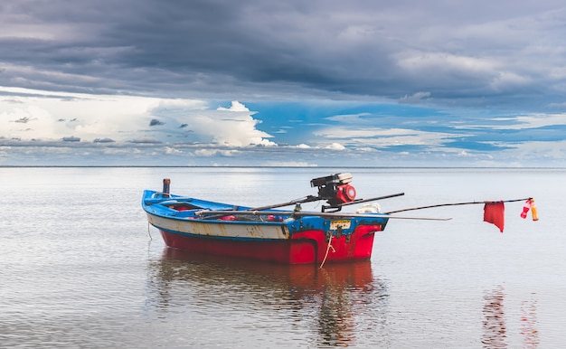 Barco de pesca con poca iluminación y cielo oscuro.