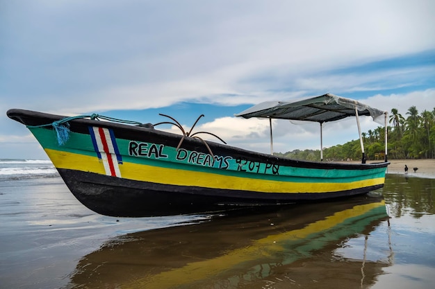 Barco de pesca reflejado en la orilla de una playa solitaria