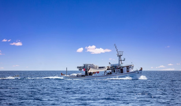 El barco de pesca regresa Las velas de arrastre en el Egeo El mar ondulado El fondo del cielo azul Las Cícladas Grecia