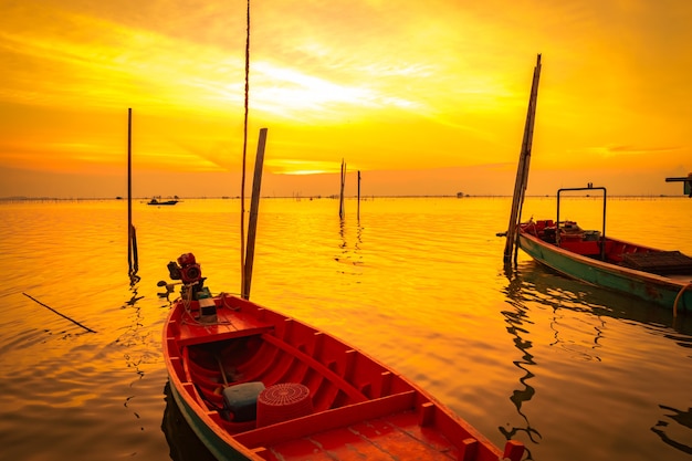 Barco de pescador flotando en el mar cerca de la caña de bambú al atardecer