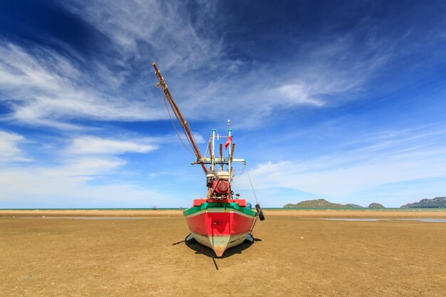 Barco de pescadores en la playa de arena y cielo azul