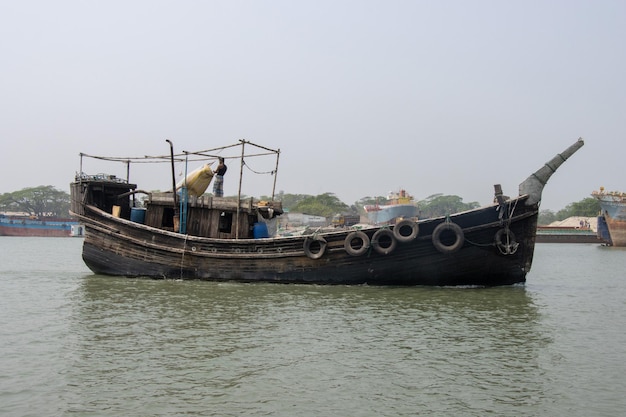 Barco de pescadores del sudeste asiático que atraviesa un río Vista lateral del antiguo arrastrero de pesca de madera Hermosa vida rural y concepto de transporte fluvial Barco de madera que atraviesa un canal