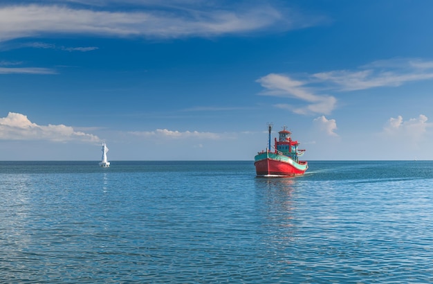 Barco pesquero de madera grande rojo en el mar con iluminación solar al aire libre y cielo azul.