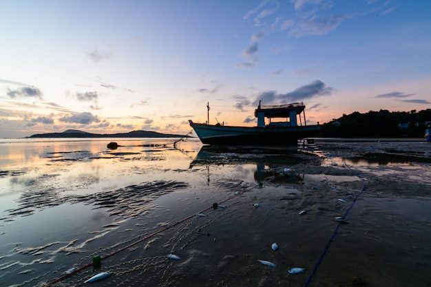 Un barco en la playa y el amanecer.