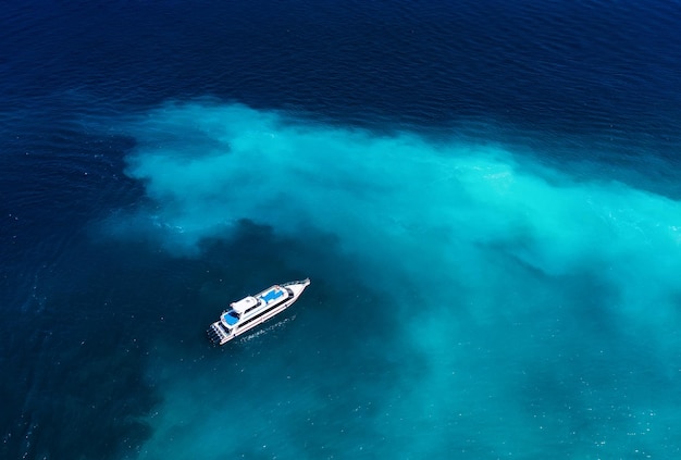 Barco rápido no mar em Bali Indonésia Vista aérea do barco flutuante de luxo na água turquesa transparente no dia ensolarado Seascape do ar Vista superior do drone Imagem de viagem