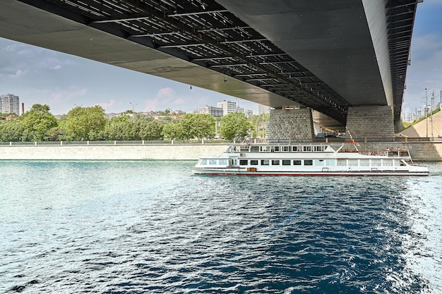 Barco de río moderno en el fondo del puente en la ciudad El barco navega en el río de la ciudad