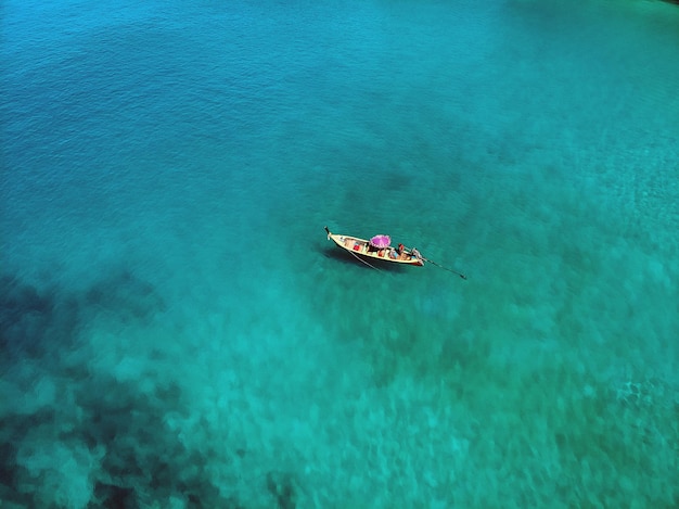 Un barco solitario flota pacíficamente en medio de un vasto océano azul, vista aérea