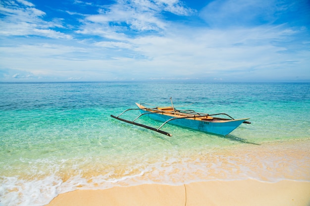 Barco tradicional filipino en una playa blanca en el mar