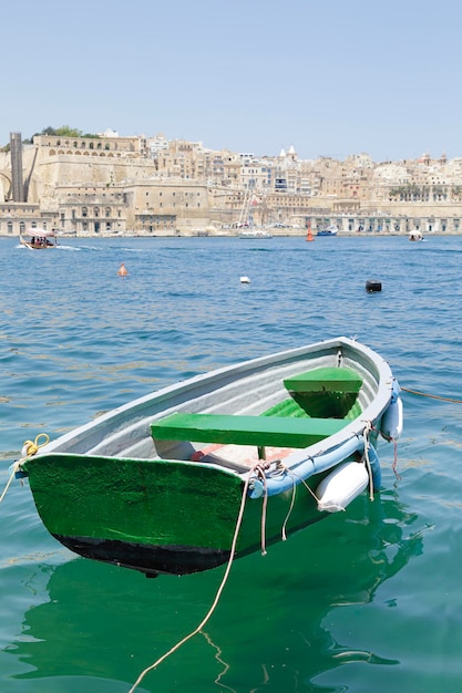 Barco tradicional maltés de la ciudad de La Valeta visible en el fondo visto desde Senglea Malta