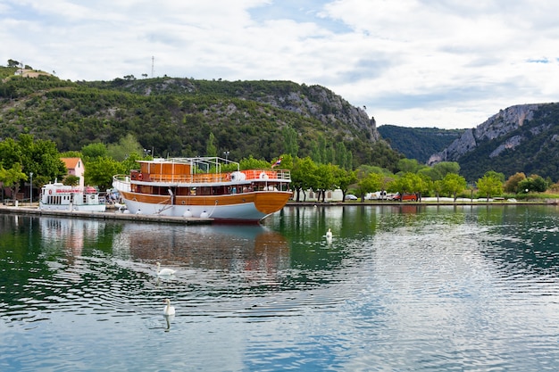 Barco turístico y cisnes en Skradin, Croacia. Tiro horizontal