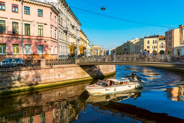 Barco turístico navega bajo el puente del Banco con grifos en el canal Griboyedov. San Petersburgo.