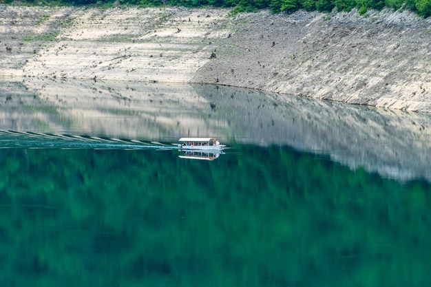 Un barco turístico con turistas nada a lo largo del pintoresco lago entre el cañón