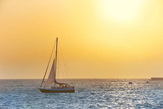 Barco de vela contra el mar al atardecer. Colorido paisaje marino.