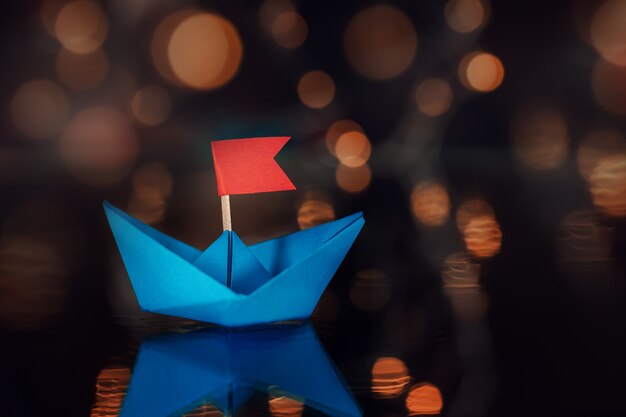 Barco de vela de papel azul en la oscuridad