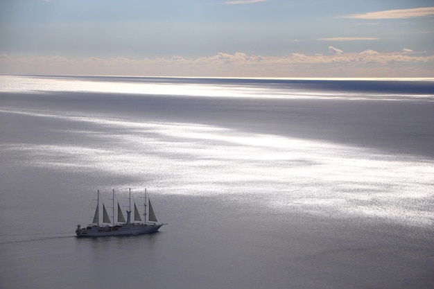 Barco con velas navegando por el mar en un día nublado