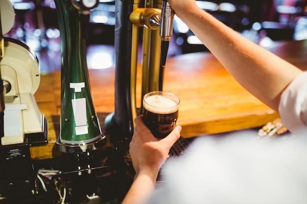 Foto barcoque segurando vidro abaixo da torneira de distribuição de cerveja