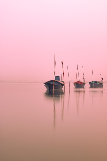 Foto barcos anclados en un río al atardecer