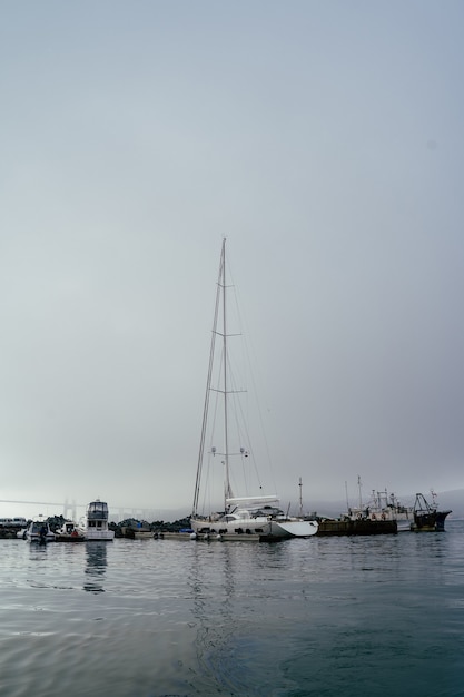 Barcos atracados no porto, veleiro, nevoeiro alto, manhã
