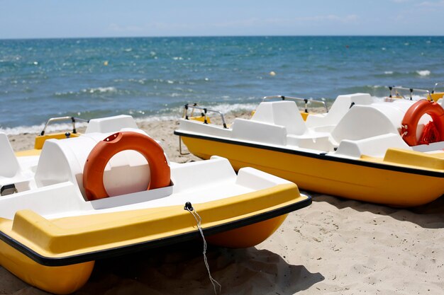 Barcos catamarã na praia de areia com bóias salva-vidas