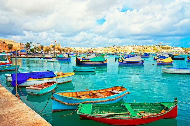 Barcos coloridos de Luzzu en el terraplén del puerto de Marsaxlokk, la bahía del mar Mediterráneo, isla de Malta