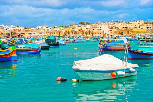 Barcos coloridos de Luzzu en el terraplén del puerto de Marsaxlokk en la bahía del mar Mediterráneo, isla de Malta