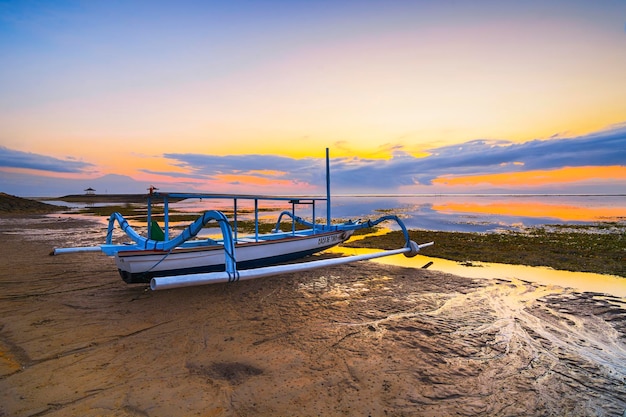 Barcos de pesca jukung balineses tradicionais na praia de Sanur durante o belo nascer do sol em Bali, Indonésia