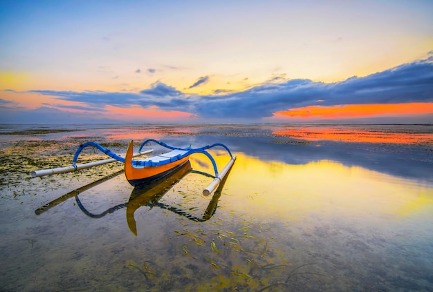 Barcos de pesca jukung balineses tradicionais na praia de Sanur durante o belo nascer do sol em Bali, Indonésia