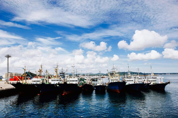 Barcos de pesca no porto de mar azul com céu azul claro e nuvens