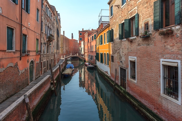 Barcos en el estrecho canal entre coloridas casas históricas en Venecia.