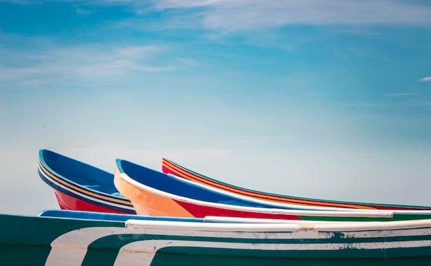 Barcos de madera estacionados en la arena, coloridos barcos de pesca estacionados cerca del océano, primer plano de barcos varados en la orilla del océano con cielo azul y espacio de copia