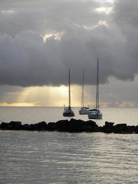 Barcos en el mar contra un cielo nublado durante la puesta de sol