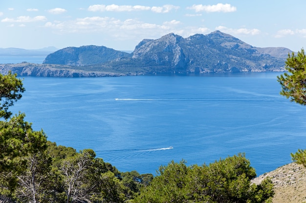 Los barcos a motor se deslizan sobre la superficie del mar con el telón de fondo de las altas montañas