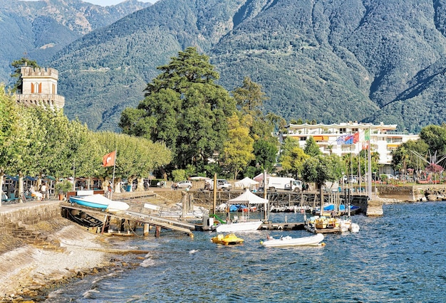 Barcos a motor y el terraplén del lujoso resort Ascona en el lago Maggiore en el cantón de Ticino en Suiza. gente en el fondo