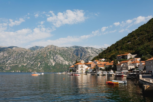 Barcos en el muelle de perast con el telón de fondo de las montañas de montenegro