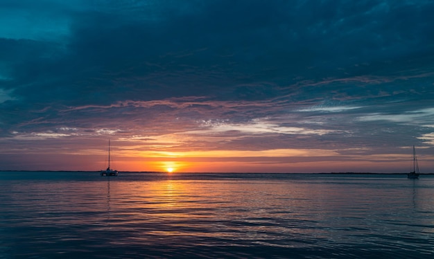 Barcos no mar ao pôr do sol veleiros com velas iate oceânico navegando ao longo da água