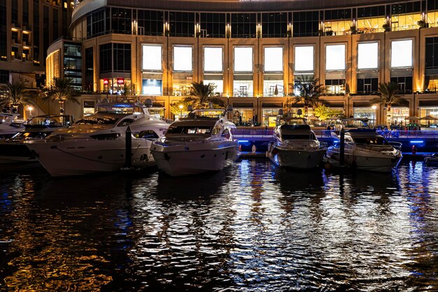 Los barcos en el puerto de Dubai Marina por la noche en luces brillantes