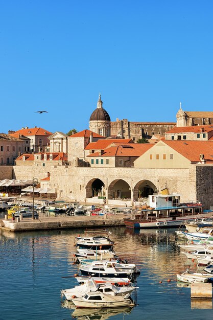 Barcos en el Puerto Viejo en el Mar Adriático en Dubrovnik, Croacia. La gente y la Catedral de Dubrovnik al fondo