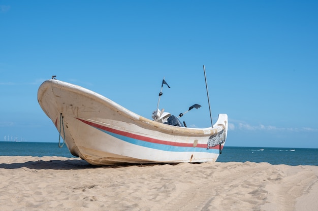 Barcos de rayas atracados en la playa, cielo azul, mar y playa