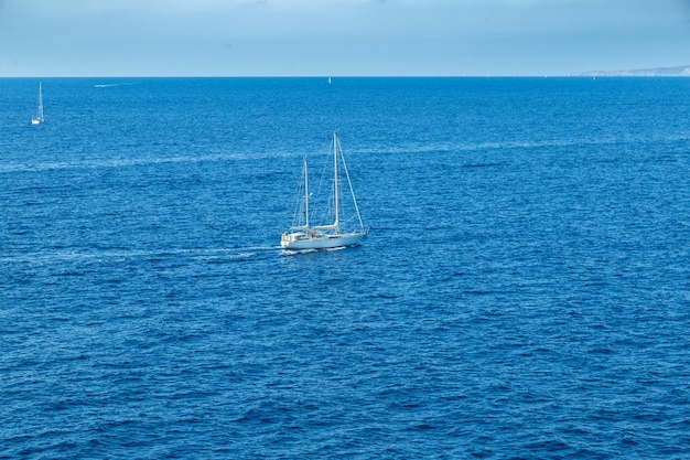 Barcos de vela en aguas abiertas de mar azul con cielo azul claro