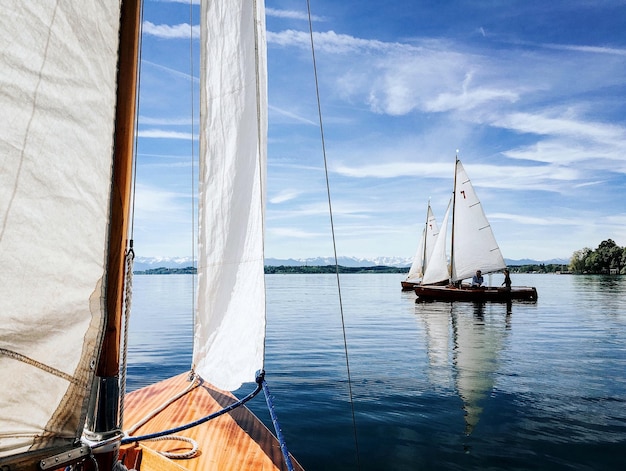 Barcos de vela navegando en el río contra un cielo nublado